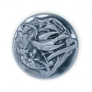 May include: A round, gray ceramic plate with a raised design of a bird and flowers. The design is in a light gray color and is very detailed.