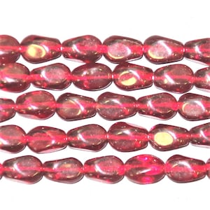 May include: Close-up of a strand of translucent, teardrop-shaped beads in shades of red and burgundy. The beads are strung on a thin, red cord, creating a repeating pattern. The beads have a glossy finish and reflect light.