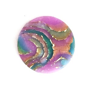 May include: A round, pink, blue, and gold resin cabochon with a swirling, marbled pattern.
