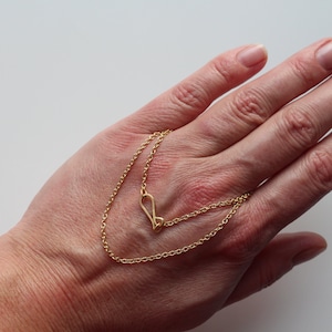 May include: A gold chain necklace with a heart-shaped pendant.