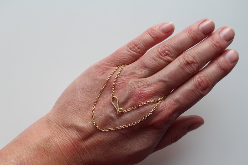 May include: A gold chain necklace with a heart-shaped pendant.