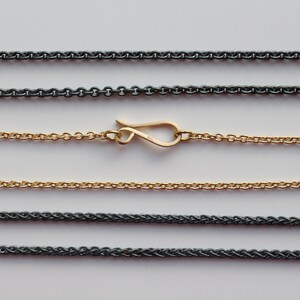 May include: Five different chain styles, including a gold chain with a lobster clasp. The chains are laid out horizontally on a white background.