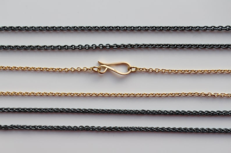 May include: Five different chain styles, including a gold chain with a lobster clasp. The chains are laid out horizontally on a white background.