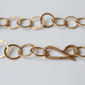 May include: A gold chain necklace with a hammered finish and a lobster clasp closure.