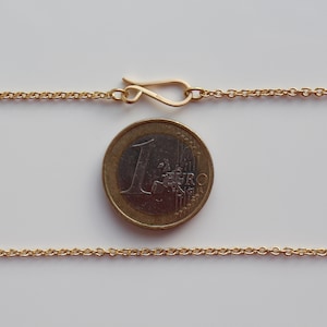 May include: A gold chain necklace with a lobster clasp closure. The chain is about the size of a Euro coin.