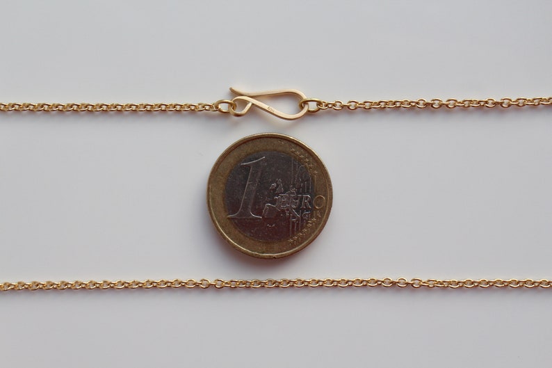 May include: A gold chain necklace with a lobster clasp closure. The chain is about the size of a Euro coin.