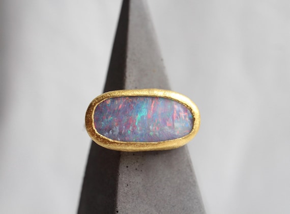 Boulder Opalring aus 24k Feingold, Opal Cabochon Ring, 750 Goldring mit 999 Goldfassung und australischem Opal in violetter Farbe mit Rot