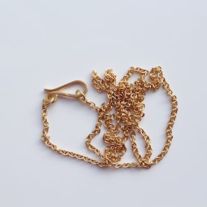 May include: A gold chain necklace with a lobster clasp closure.