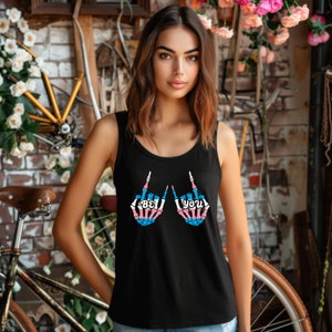 Op de afbeelding: Zwart tanktop met een afbeelding van twee skelethandjes die de middelvinger opsteken. De handen zijn gekleurd in de kleuren van de transgender pride-vlag. De tekst "Be You" staat op de handen.