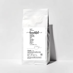 May include: A white coffee bag with a label featuring the word "beautiful" in cursive script. The label also includes text from Ecclesiastes 3:11 and a line drawing of a coffee cup. The bag is filled with Colombian coffee.