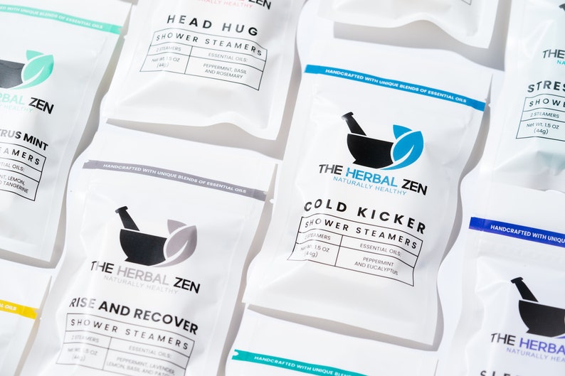 May include: A variety of white, resealable pouches with black text and graphics. The pouches contain shower steamers with different scents and essential oils. The text on the pouches includes "The Herbal Zen", "Naturally Healthy", "Head Hug", "Cold Kicker", "Rise and Recover", "Citrus Mint", "Stress Relief", "Sleep", and "Shower Steamers".