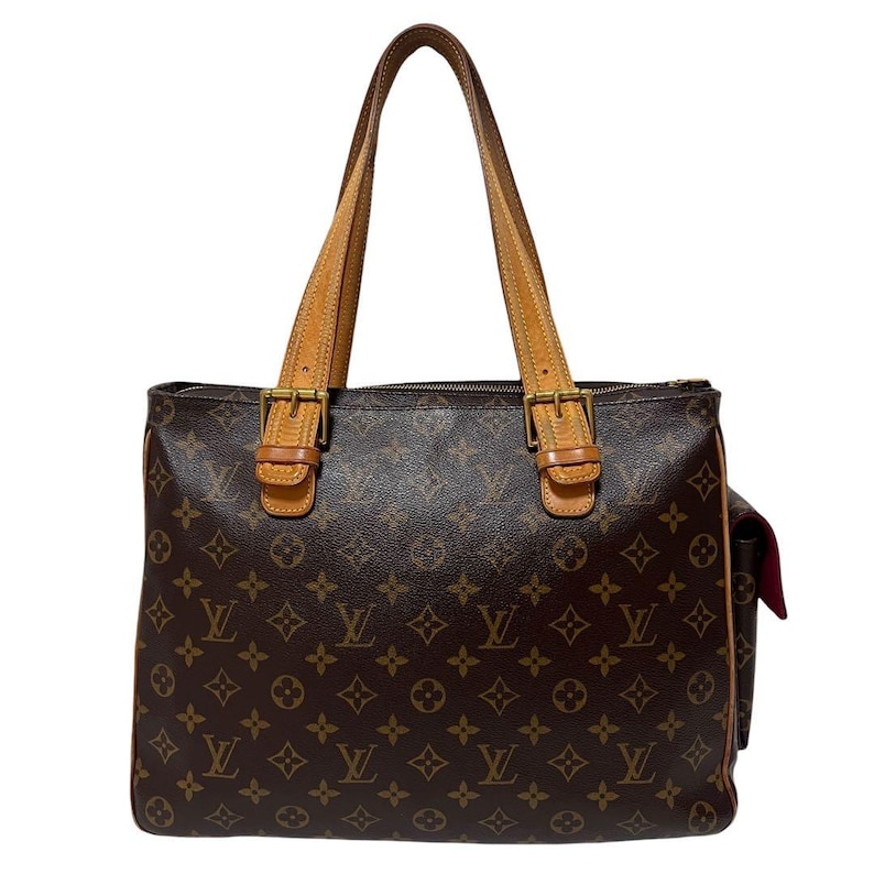 Może przedstawiać: Brązowa torba typu tote z monogramem, z jasnobrązowymi sk&oacute;rzanymi uchwytami i wykończeniami. Torba ma zapięcie na zamek błyskawiczny u g&oacute;ry i dwie klamry z przodu. Z boku po prawej stronie widoczna jest kieszeń.