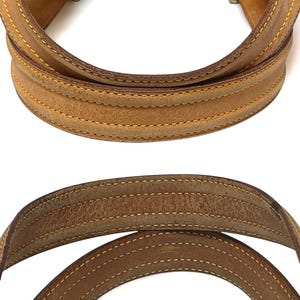 Może przedstawiać: Zbliżenie dw&oacute;ch sk&oacute;rzanych uchwyt&oacute;w do torby. G&oacute;rny uchwyt jest w jaśniejszym odcieniu brązu, podczas gdy dolny uchwyt jest ciemniejszy. Oba uchwyty mają widoczne szwy z kontrastującą ż&oacute;łtą nicią. Sk&oacute;ra nosi ślady użytkowania.