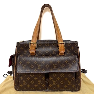 Może przedstawiać: Brązowa torba typu tote z monogramem z pł&oacute;tna z dwiema przednimi kieszeniami i jasnobrązowymi sk&oacute;rzanymi akcentami. Torba posiada dwa g&oacute;rne uchwyty, złote okucia i zapięcie na zamek błyskawiczny. Wnętrze jest jasnobrązowe.