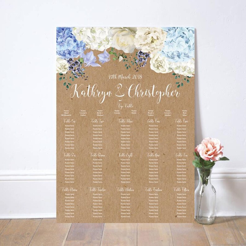 May include: A wedding seating chart printed on a kraft paper background. The top features floral arrangements in white and blue. The names "Kathryn & Christopher" are written in elegant script. The date "17th March 2018" is also displayed.