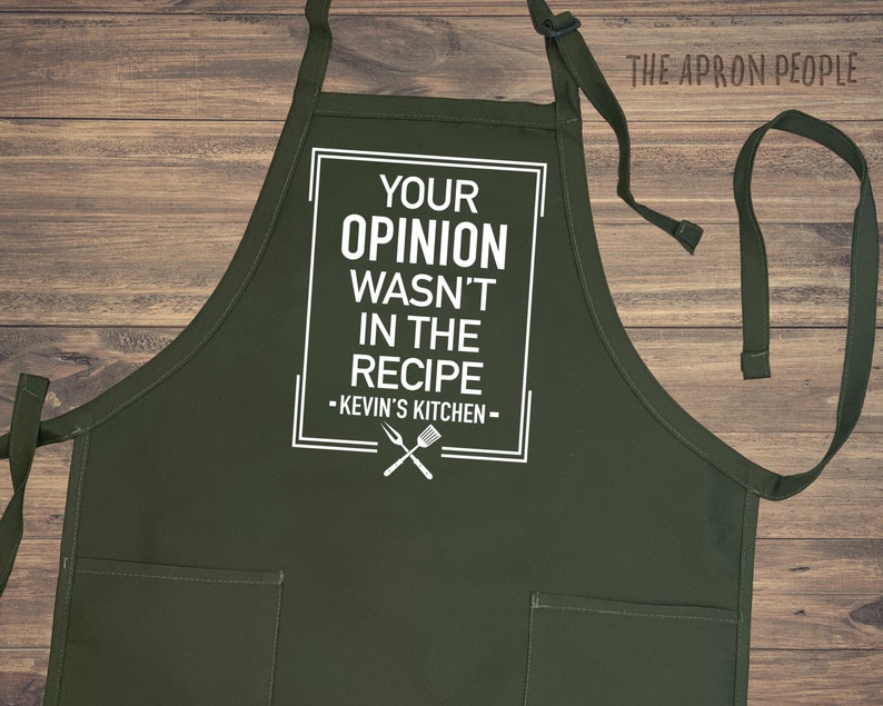 A custom made apron with adjustable over the head neck strap with waist side ties and two patch pockets prin phrase “your opinion wasn’t in the recipe” and your chosen name