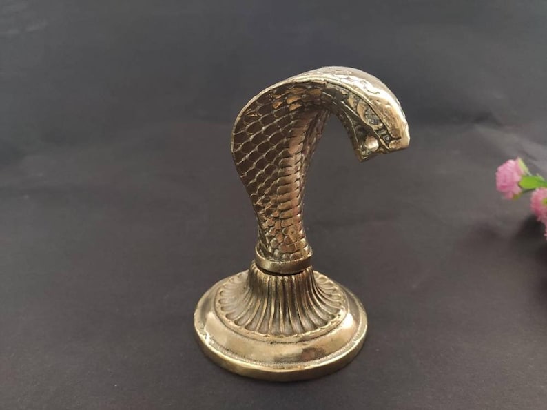 Brass hooded snake figurine with arched neck on a ribbed pedestal, ideal for desk or office decor.
