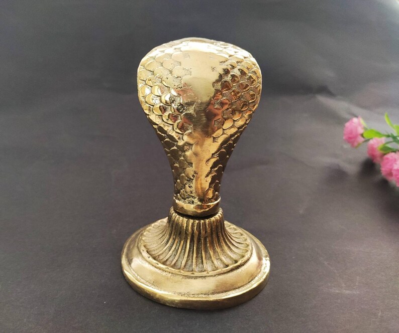 Brass hooded snake figurine with arched neck on a ribbed pedestal, ideal for desk or office decor.