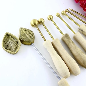 Könnte beinhalten: Ein Satz von 9 Werkzeugen aus Messing in Blatt- und Kugelform mit Holzgriffen. Die Werkzeuge werden verwendet, um Blatt- und Blumenmuster in Polymer Clay zu erstellen.