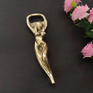 May include: A gold-colored bottle opener shaped like a stylized female figure.