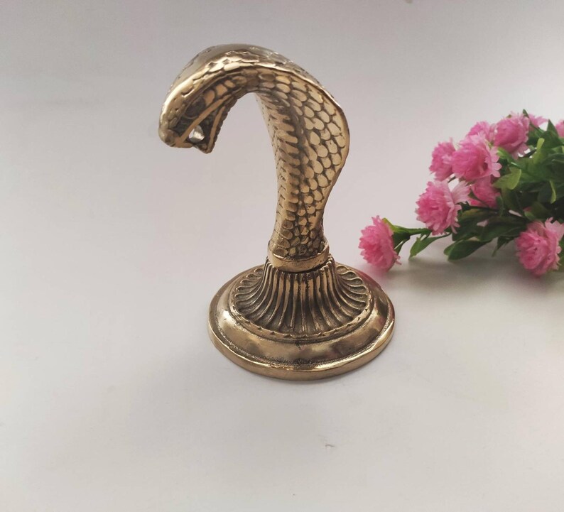 Brass hooded snake figurine with arched neck on a ribbed pedestal, ideal for desk or office decor.