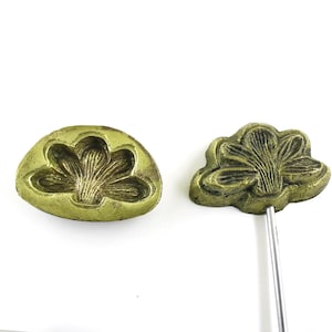 May include: Two antique brass molds for making flower-shaped pastries. One mold is a flat, oval-shaped mold with a raised flower design. The other mold is a three-dimensional flower shape on a metal rod.