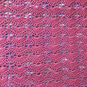 May include: A close-up of a crocheted blanket with a pink and purple color scheme. The blanket is made with a repeating pattern of small circles.