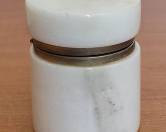 May include: A white marble jar with a brass lid. The jar has a natural veining pattern.