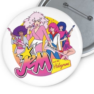 以下が含まれることがあります： ジェムとホログラムズの漫画のバンドのカラフルな画像が描かれた白いボタン。画像には、楽器を演奏するバンドメンバーと、ピンクと白の文字で書かれたバンド名が描かれています。
