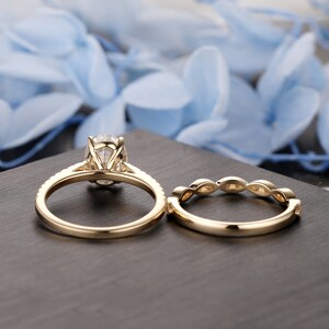 Puede incluir: Un conjunto de dos alianzas de oro. El anillo de compromiso presenta una gran piedra central de forma ovalada con piedras m&aacute;s peque&ntilde;as engastadas en pav&eacute;. La alianza de boda tiene un dise&ntilde;o delicado con peque&ntilde;as piedras redondas engastadas en pav&eacute;.