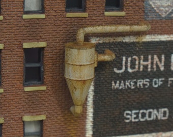 May include: A close-up of a brick building with a sign that reads "JOHN B McLEN MAKERS OF FINE CLOCKS AND SECOND AND GOODSO". There is a rusty pipe and a rusty metal cylinder on the side of the building.