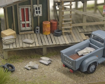 May include: A gray pickup truck with a wooden bed is parked in front of a small wooden shed. The truck is loaded with bags of cement. A sign on the shed reads "No Parking Loading Zone".