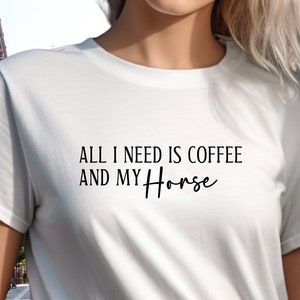 May include: White t-shirt with black text that reads "All I need is coffee and my Horse".