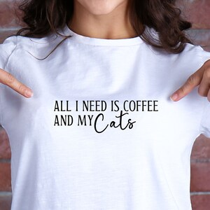 Peut inclure: T-shirt blanc avec un texte noir qui dit "Tout ce dont j'ai besoin, c'est du café et de mes chats".