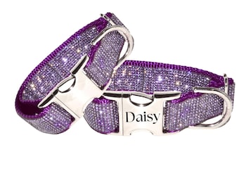 May include: Two purple pet collars covered in shimmering crystals. Each collar features a polished silver-tone metal side-release buckle. One buckle is engraved with the name Daisy in a black serif font. Both collars include a silver D-ring.
