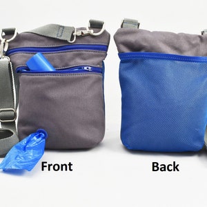 Op de afbeelding: Grijze en blauwe hondenuitlaattas met een schouderriem. De voorkant van de tas heeft een grijze zak met een blauwe rits en een blauwe rol afvalzakken. De achterkant van de tas is blauw.