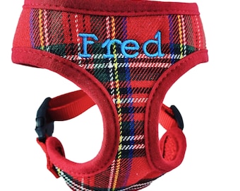 Op de afbeelding: Een rood huisdierentuigje met een ruitpatroon in groen, blauw en geel. Het tuigje heeft een effen rode stoffen rand en een zwarte plastic gesp. De naam Fred is in lichtblauw garen op het borstgedeelte van het tuigje geborduurd.