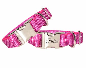 Könnte beinhalten: Zwei leuchtend pinke Haustierhalsbänder, die mit kleinen reflektierenden Kristallen besetzt sind. Jedes Halsband hat eine silberfarbene Metallschnalle. Eine Schnalle ist mit dem Namen Bella in Schreibschrift graviert. Beide haben einen D-Ring.