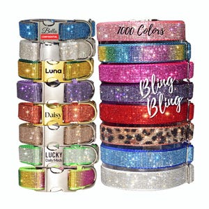 May include: A collection of pet collars covered in sparkling rhinestones in various colors including blue, silver, gold, purple, red, green, and leopard print. Some feature metal buckles with engraved names like Bella, Luna, Daisy, and Lucky.