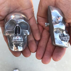 En halv dödskalle-huvdekoration i aluminium med bult på baksidan. 6,5 cm bred.