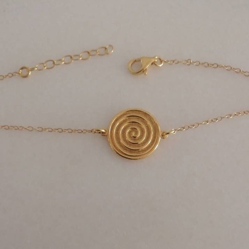 Dainty 14k gold bracelet with an eye-catching Spiral coin disc.
