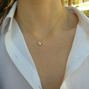 May include: A gold chain necklace with a single large, clear, round gemstone pendant.