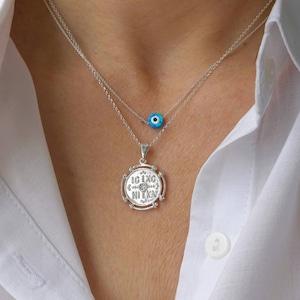 Op de afbeelding: Een zilveren ketting met een blauwe kwade oog bedel en een zilveren hanger met de inscriptie "IC XC NIKA".