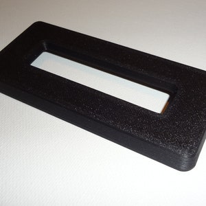 May include: Black plastic rectangular frame with a rectangular opening in the center.