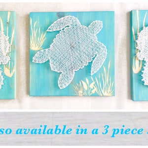 May include: Three string art pieces on a blue background. The center piece is a white turtle, and the pieces on either side are white seahorses. The text "Also available in a 3 piece set" is below the images.