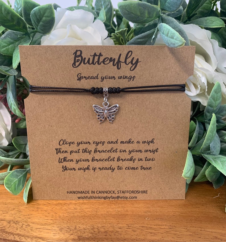 May include: A black string bracelet with a silver butterfly charm. The bracelet is tied with a knot and has a tag that reads "Butterfly Spread your wings Close your eyes and make a wish Then put this bracelet on your wrist When your bracelet breaks in two Your wish is ready to come true Handmade in Cannock, Staffordshire wishfulthinkingbyfay@etsy.com"