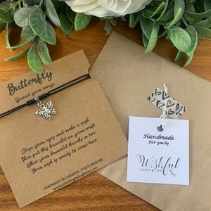 May include: A black string bracelet with a silver butterfly charm. The bracelet is packaged on a brown card with the text "Butterfly Spread your wings" and instructions on how to make a wish. The card also includes the text "Handmade in Cannock, Staffordshire wishfulthinkingbyfay@etsy.com". A separate white card with the text "Handmade for you by Wishful Thinking by Fay" is included.