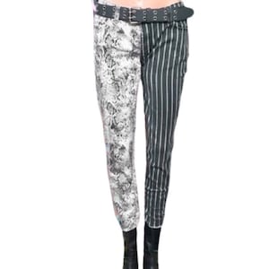 May include: Split-design pants with a snakeskin print on one leg and vertical black and white stripes on the other. The pants are secured with a black belt with silver-tone hardware. The model is wearing black boots.