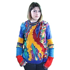 May include: A colorful sweater with a patchwork design. The sweater features a mix of blue, yellow, red, and green fabrics. The sleeves are blue with red cuffs. The sweater has a round neckline and a unique, textured appearance.