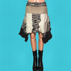 May include: A unique, asymmetrical skirt with a patchwork design. The skirt features a mix of textures and colors, including beige, black, and white knit fabrics. The skirt is paired with black boots, creating a stylish and modern look.